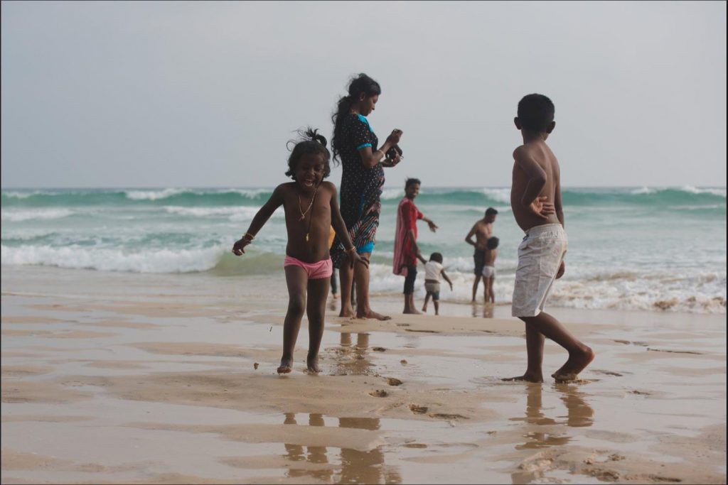 Sri Lanka photographer: kids thrilled at a sandy beach with the waves.