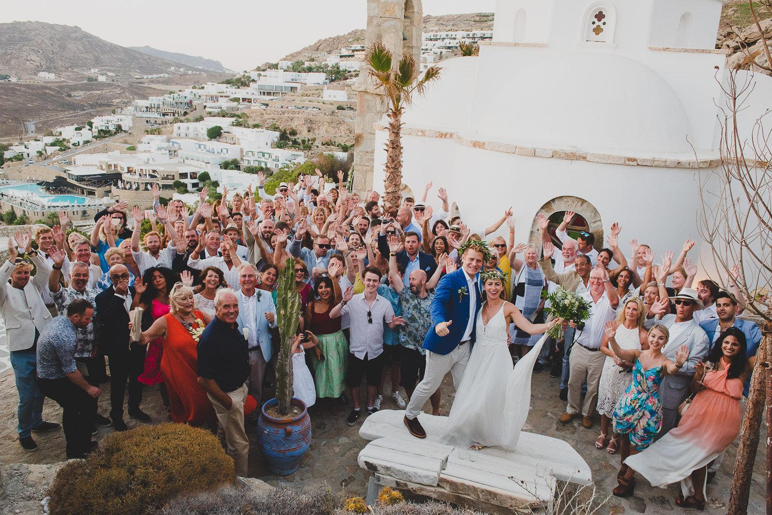 Wedding photographer Mykonos: group photo of wedding party with their hands in the air all smiling group for Mykonos wedding.
