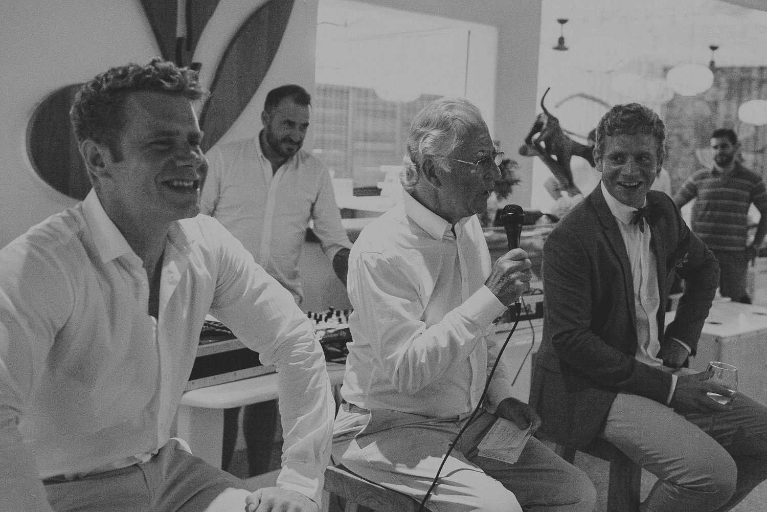Wedding photographer Mykonos: black and white photo of the father of the bride during speeches at Elia for Mykonos wedding reception.