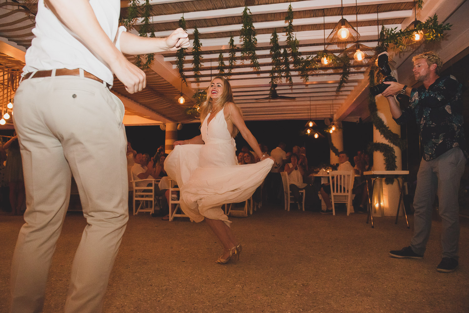 Wedding photographer Mykonos: wild first dance with bride swaying her dress at Elia during Mykonos wedding reception.