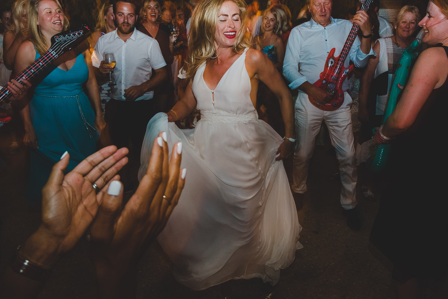 Wedding photographer Mykonos: bride on the dance floor surrounded by inflatable guitar at Elia during Mykonos wedding.
