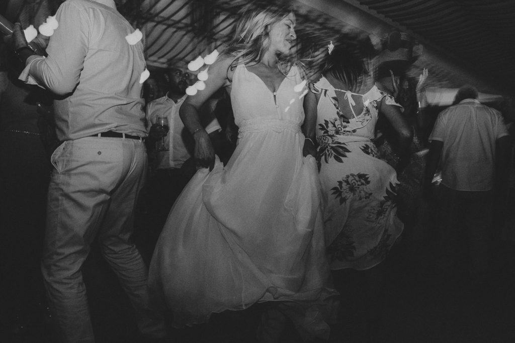 Wedding photographer Mykonos: bride in black and white dancing at Elia beach Mykonos wedding.