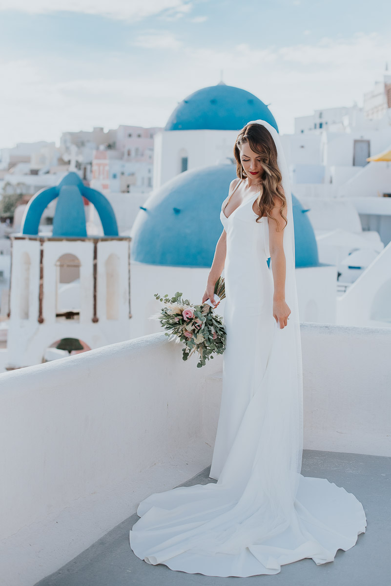 Santorini elopement photographer: bride with the blue domes by Ben and Vesna.