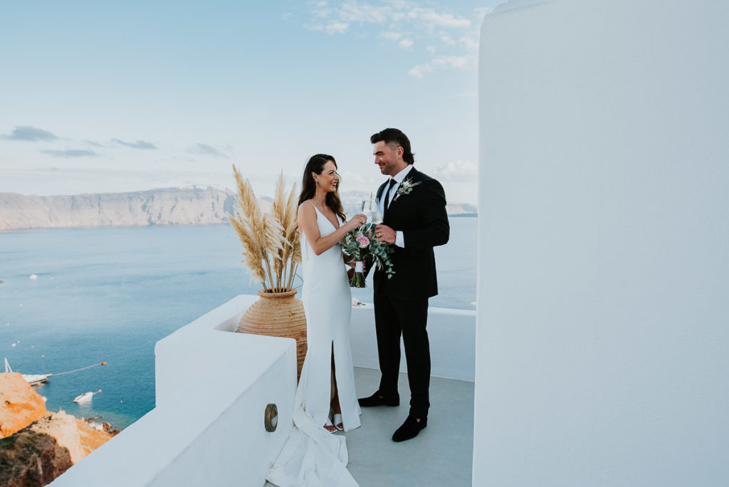 Santorini elopement photographer: couple with champagne by Ben and Vesna.