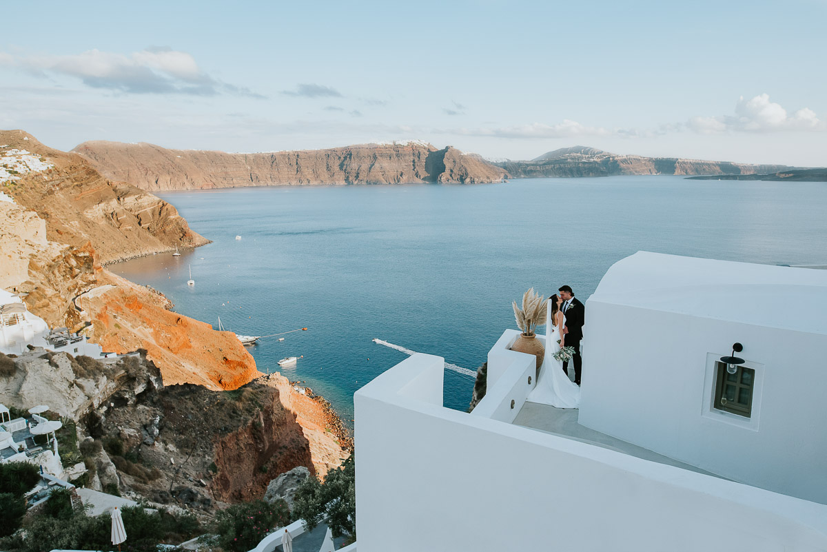 Santorini elopement photographer: couple kissing with views of Oia by Ben and Vesna.