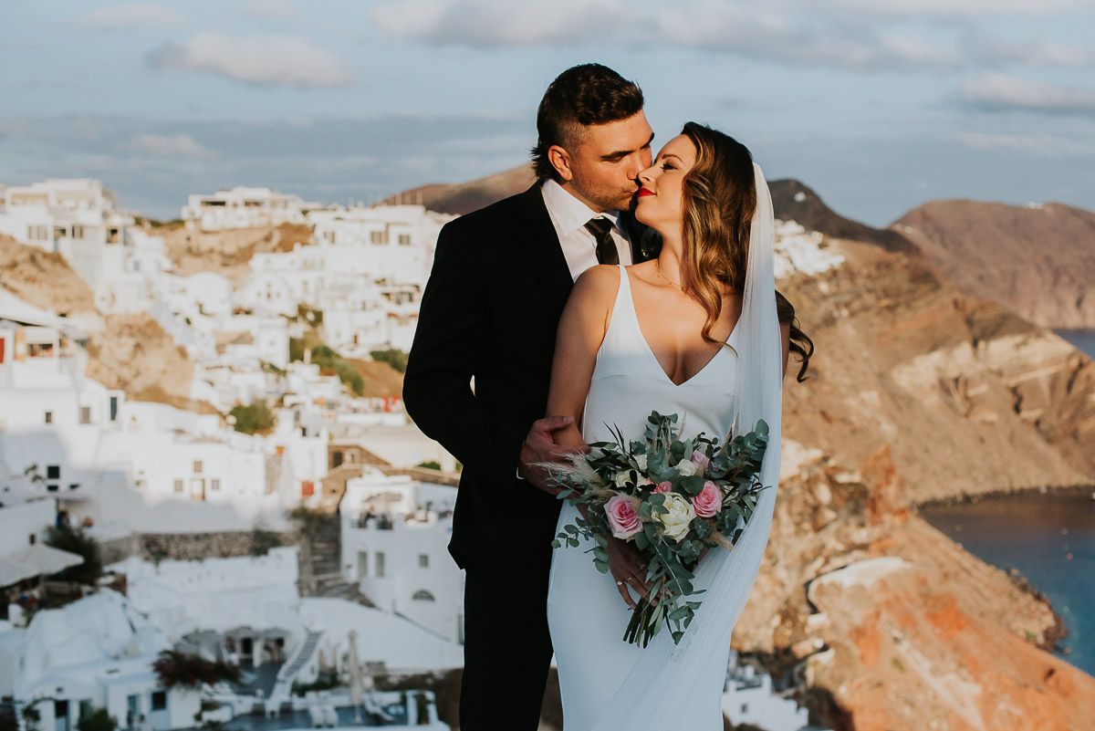 Santorini elopement photographer: couple with views of Oia by Ben and Vesna.