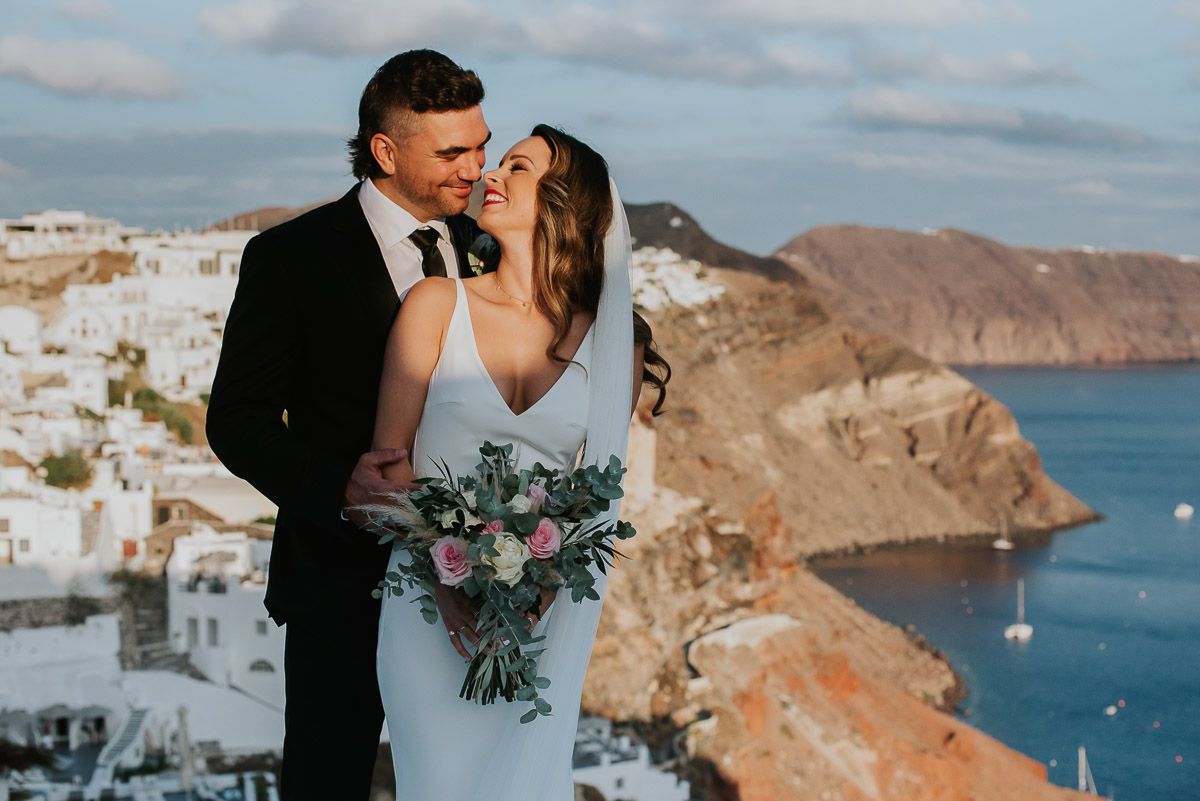 Santorini elopement photographer: couple with views of Oia by Ben and Vesna.