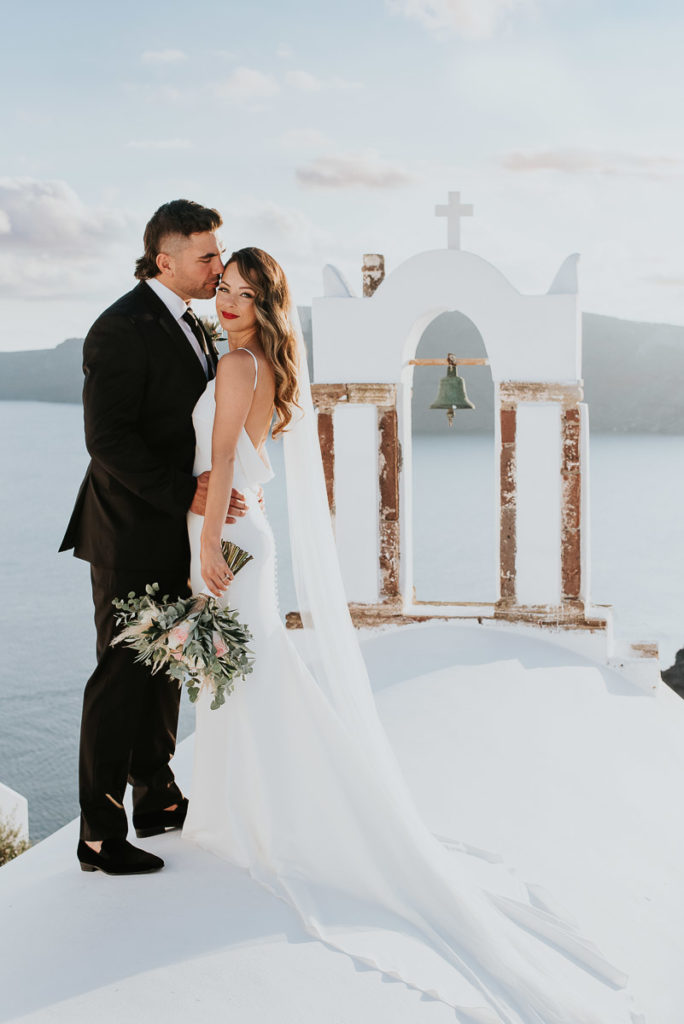 Santorini elopement photographer: couple with the bell tower by Ben and Vesna.