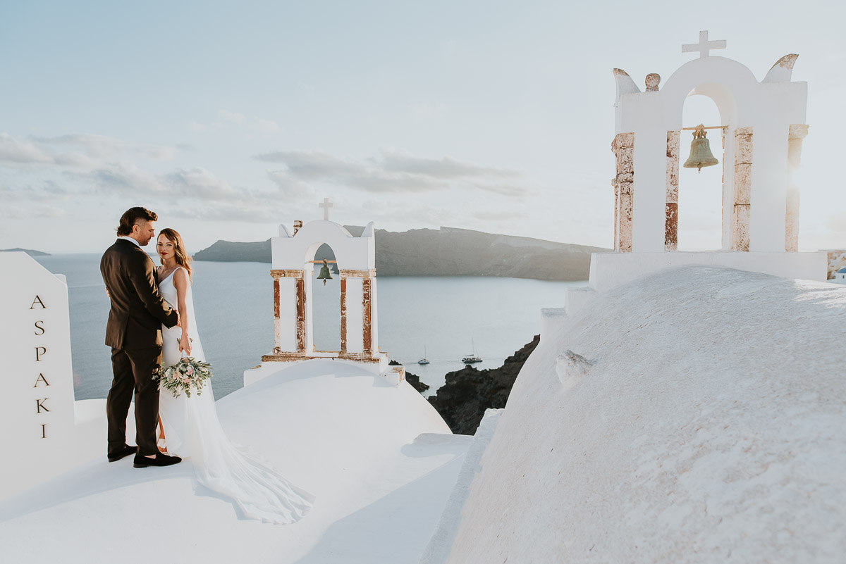 Santorini elopement photographer: couple with the bell towers by Ben and Vesna.