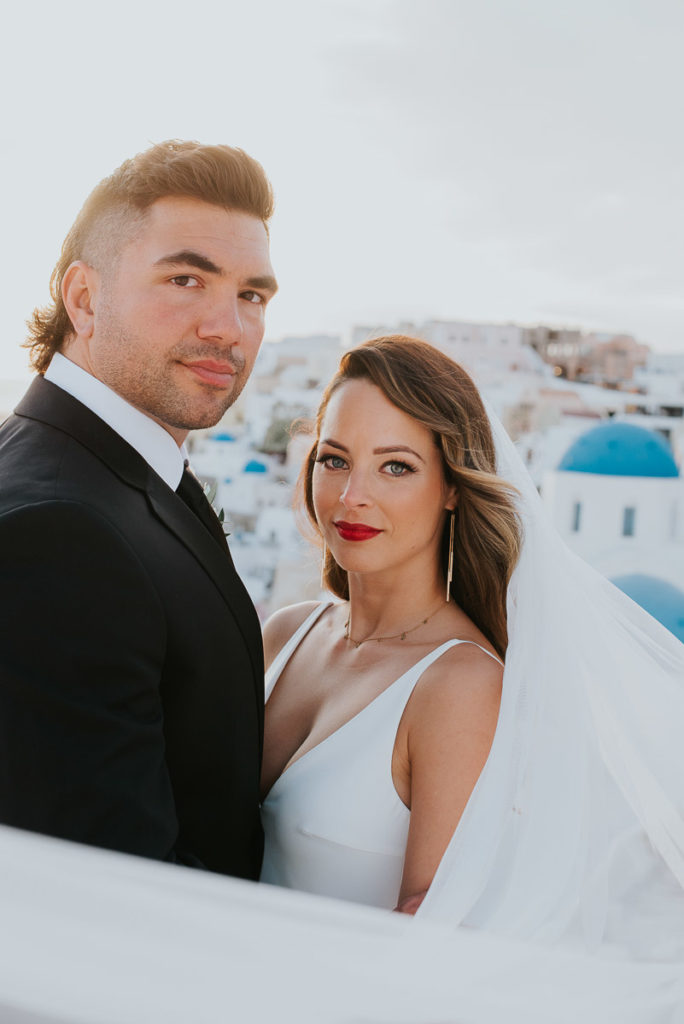 Santorini elopement photographer: portrait of the couple with the blue domes by Ben and Vesna.