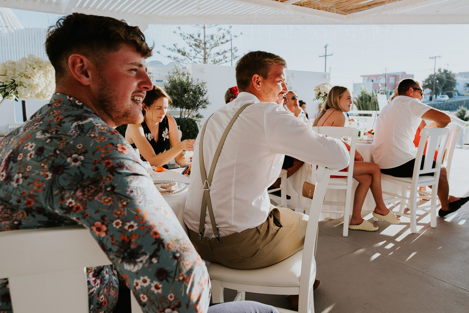 Wedding photographer Santorini: guests sat at their table as they listen to the speeches by Ben and Vesna.