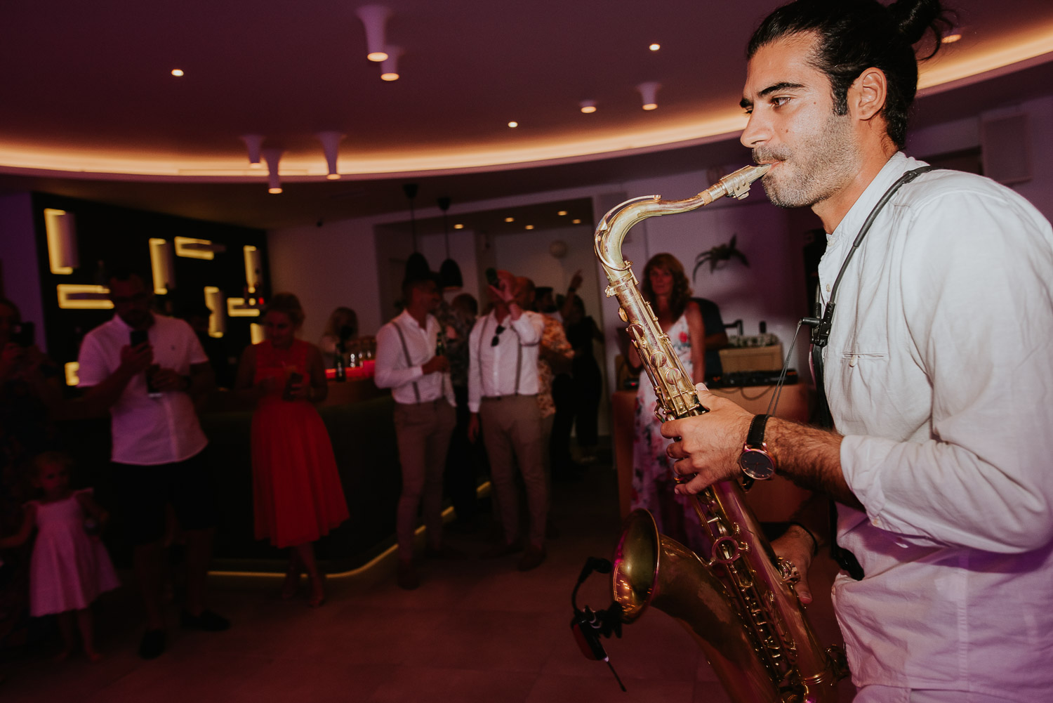 Wedding photographer Santorini: close up of the sax player surrounded by the guests on the dance floor by Ben and Vesna.