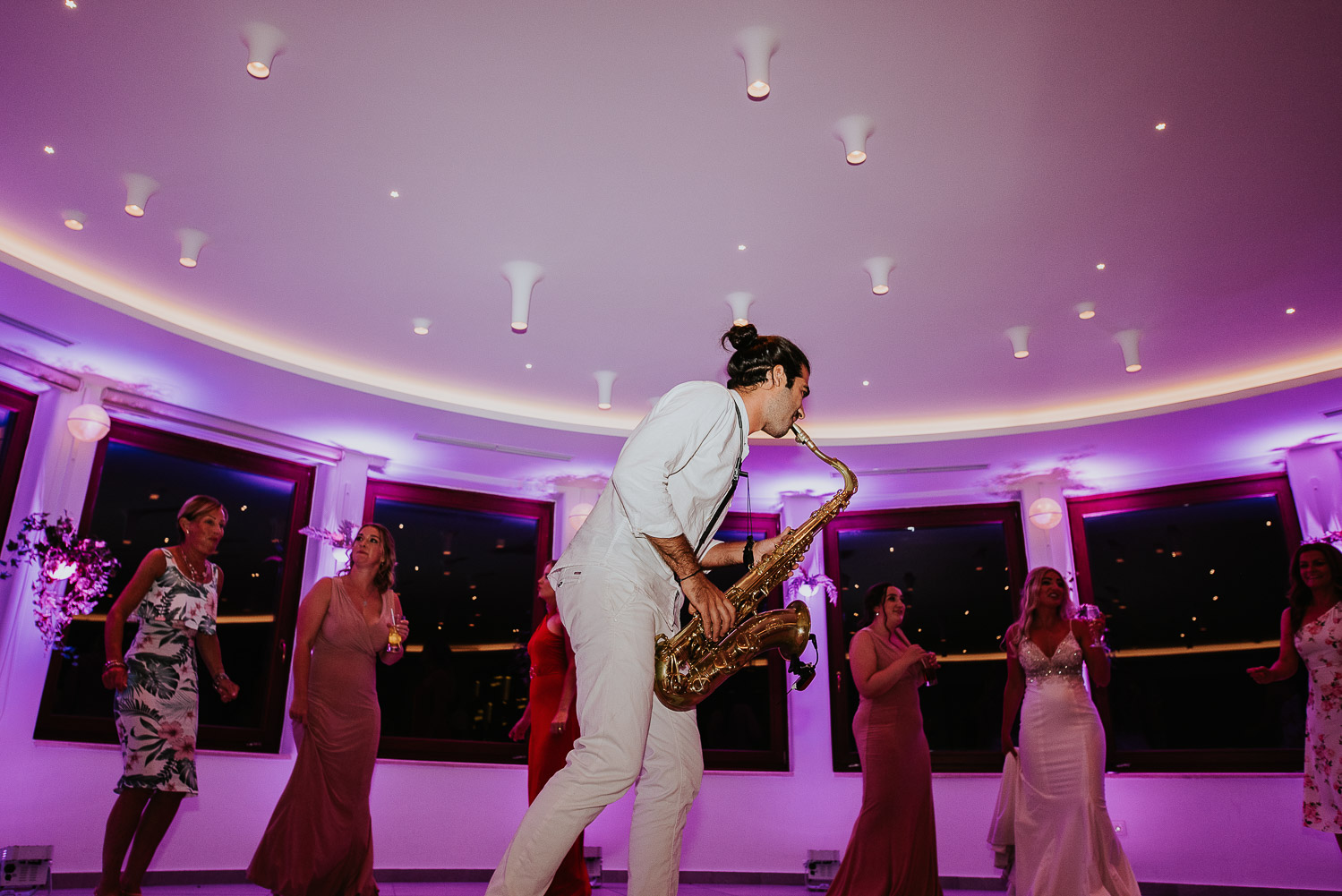 Wedding photographer Santorini: sax player surrounded by the guests on the dance floor by Ben and Vesna.