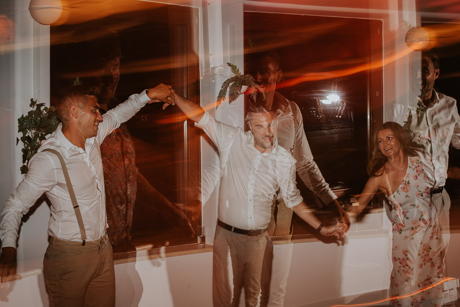 Wedding photographer Santorini: groom and the guests making wave on the dance floor in this abstract photo by Ben and Vesna.