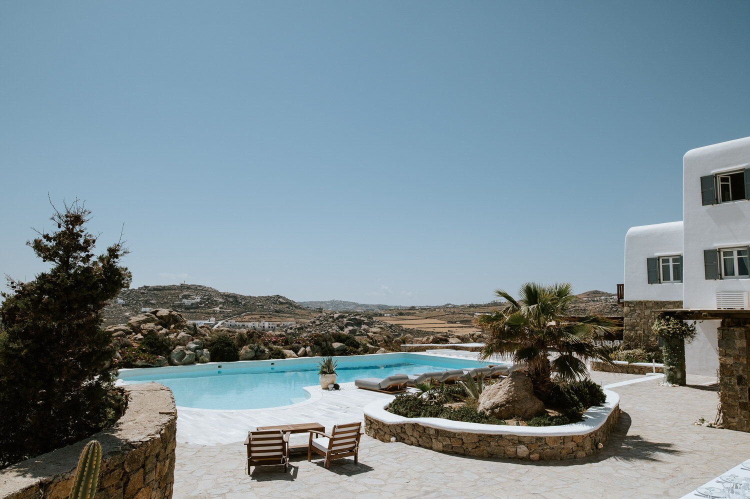 Mykonos wedding photographer: panorama of the villas and the magnificent pool in front with the views over the Mykonian landscape.