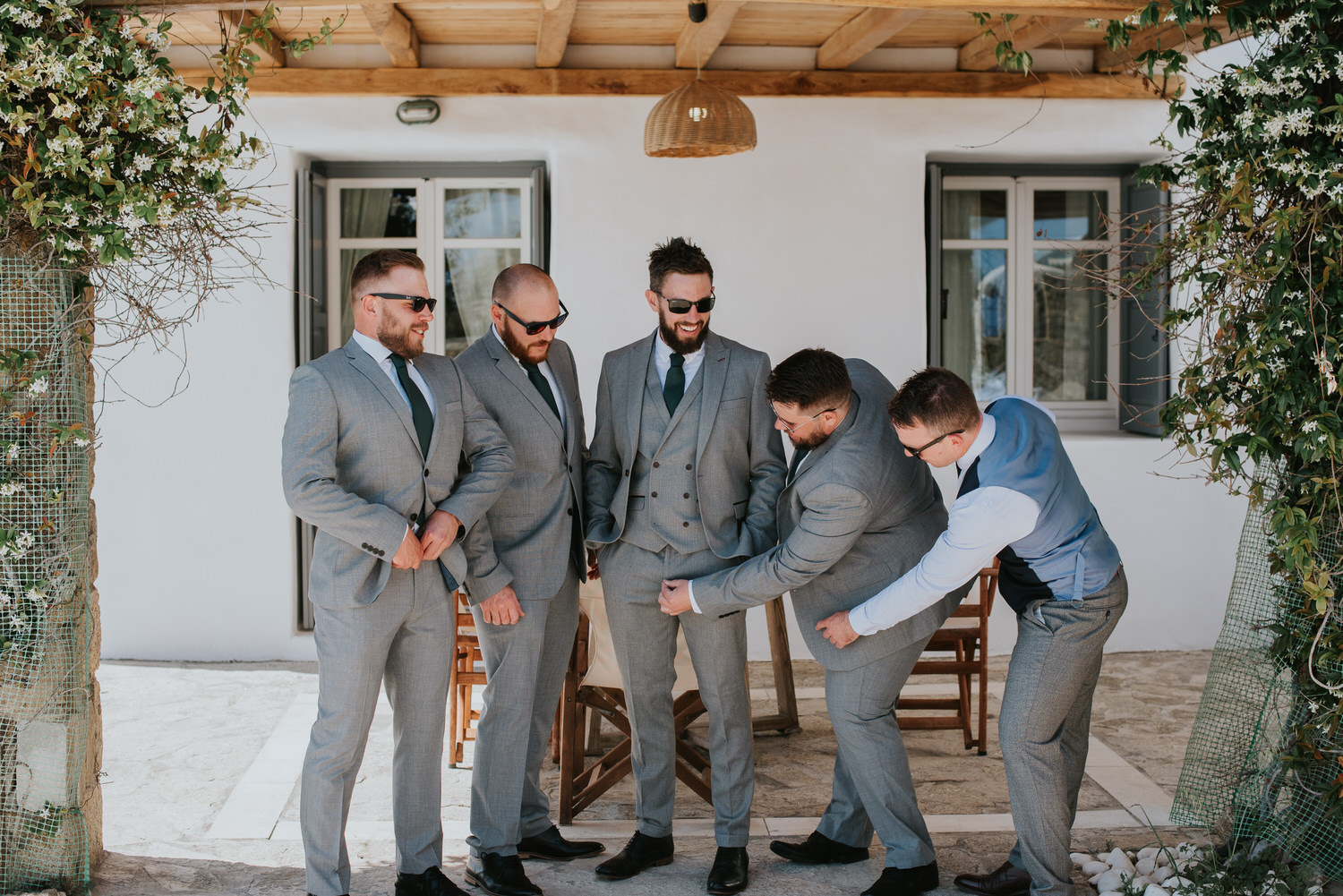 Mykonos wedding photographer: groom having a laugh with his men in front of the villa.