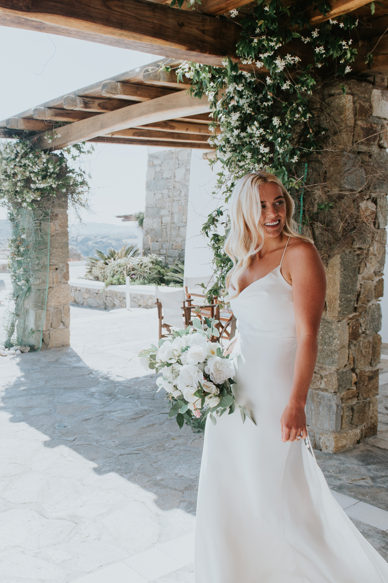 Mykonos wedding photographer: gorgeous bride nervously stepping out of villa looking back before her first look with the groom.