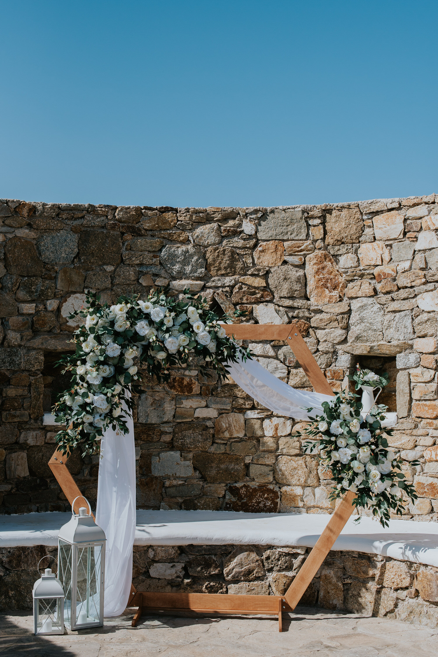 Mykonos wedding photographer: the floral arch detail against the rocky wall in the background.