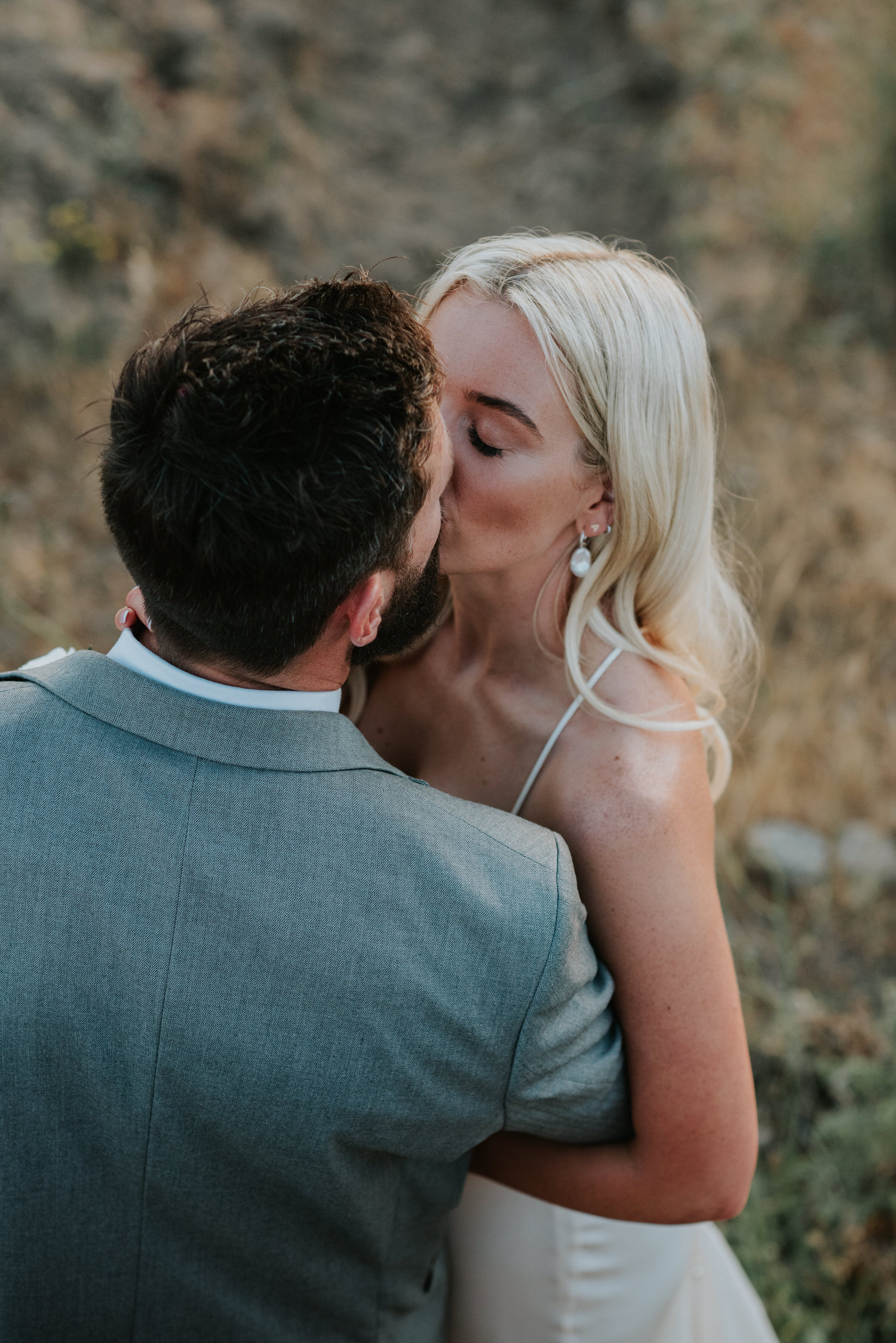 Mykonos wedding photographer: closeup of bride and groom kissing with grass around them.