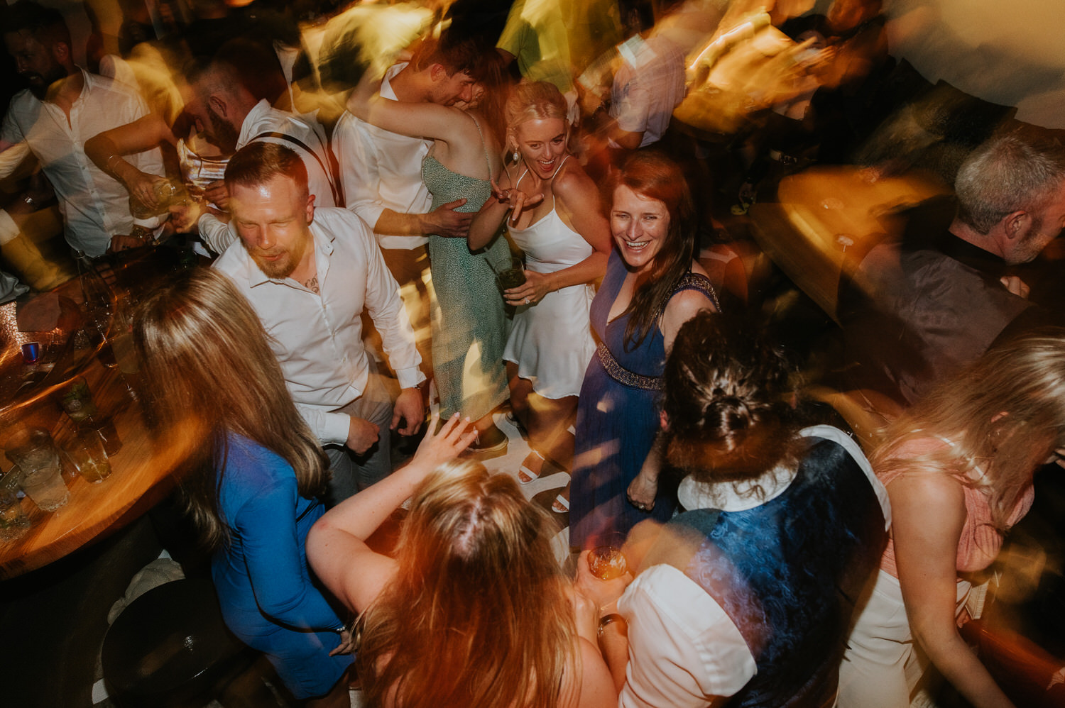 Mykonos wedding photographer: bride and her guests in high spirits on the dance floor at Scarpa bar during her Mykonos wedding celebration.