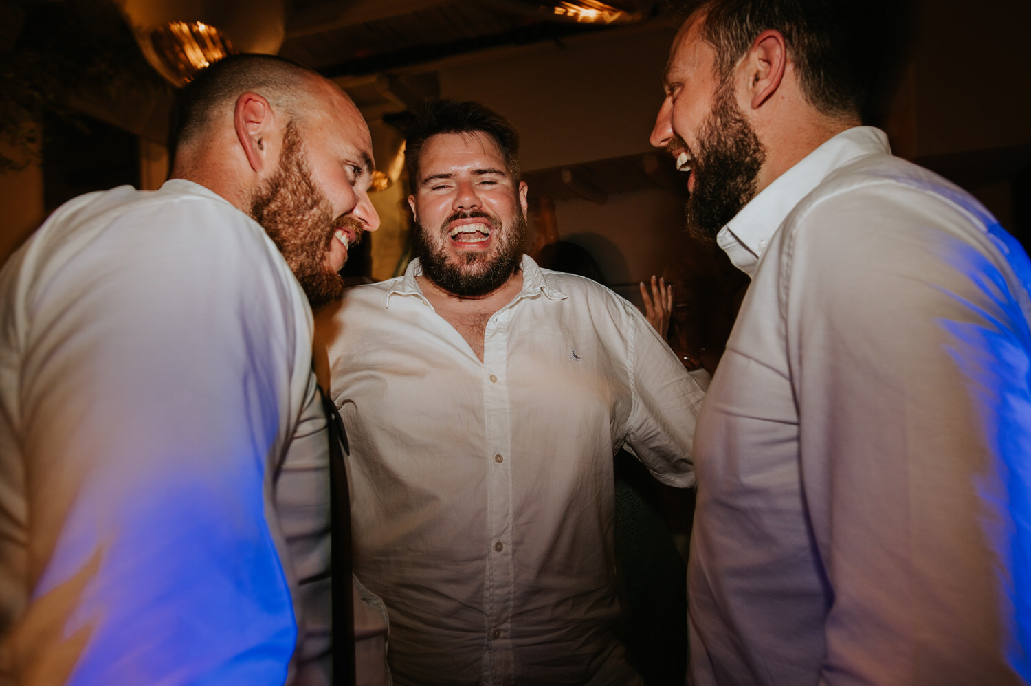 Mykonos wedding photographer: groom and his best men laughing during a night at the club.